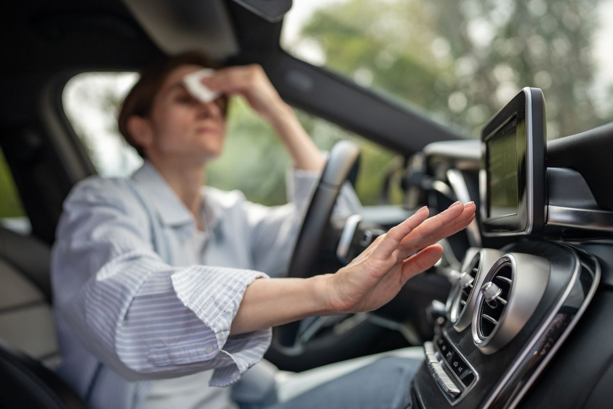 Person in a car shielding their face from bright sunlight while driving.