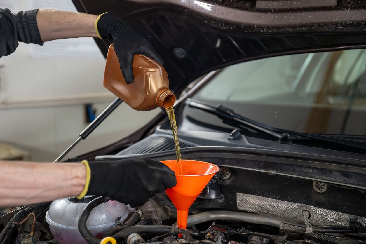 Motor oil being poured through a funnel into a car engine bay