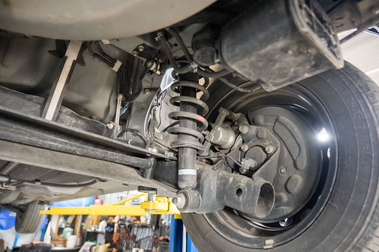 Undercarriage of a vehicle showing a suspension coil spring and rear wheel in a garage
