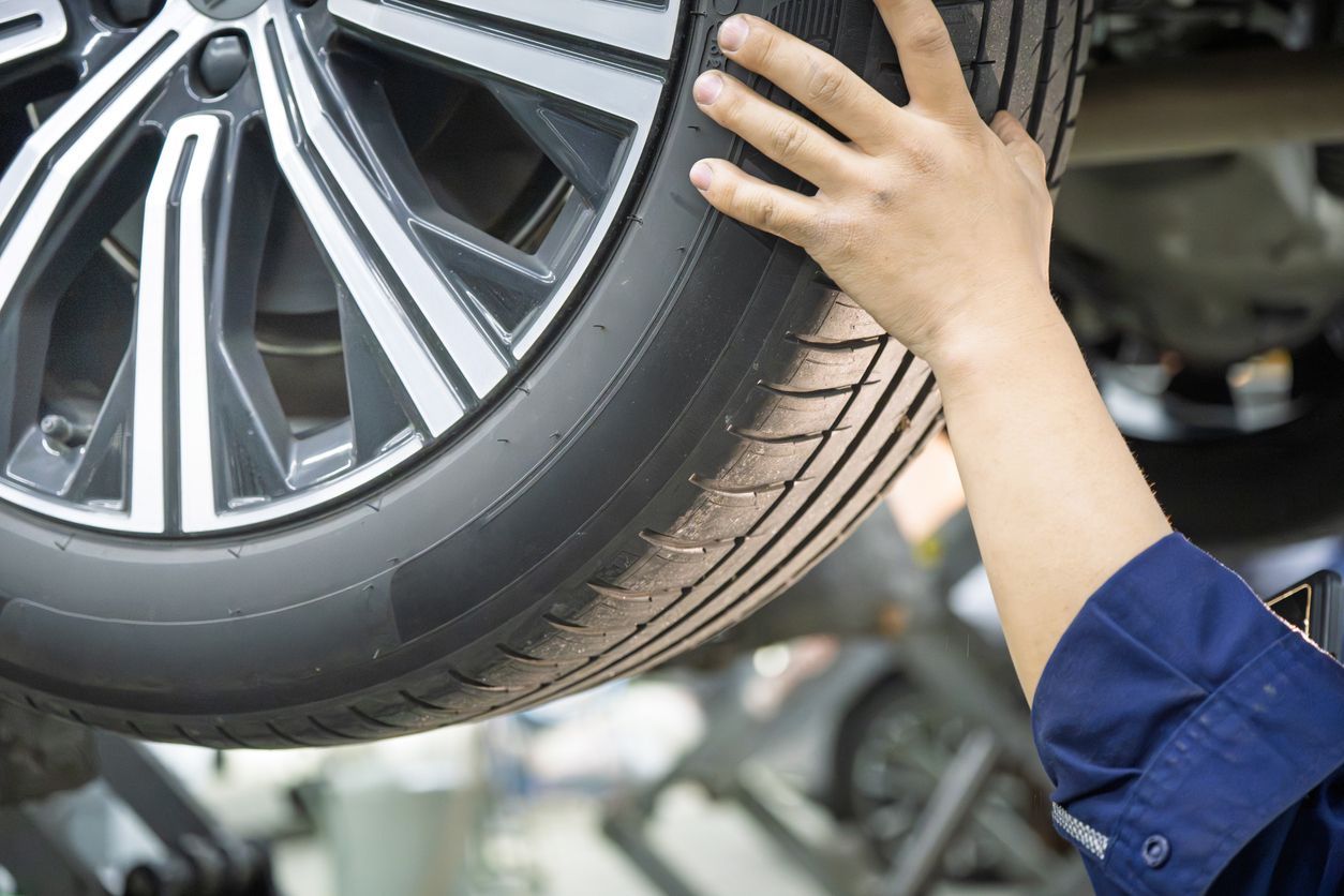 Mechanic inspecting a car tire and wheel on a lift