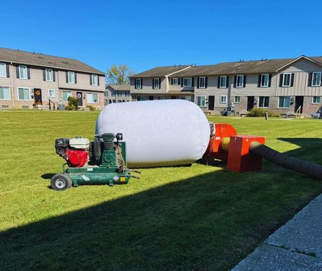 Yellow flexible tubes extend from windows on a brick building to the lawn.