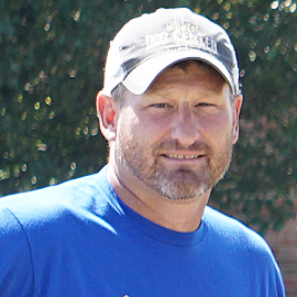 A man wearing a blue shirt and a hat that says truck worker