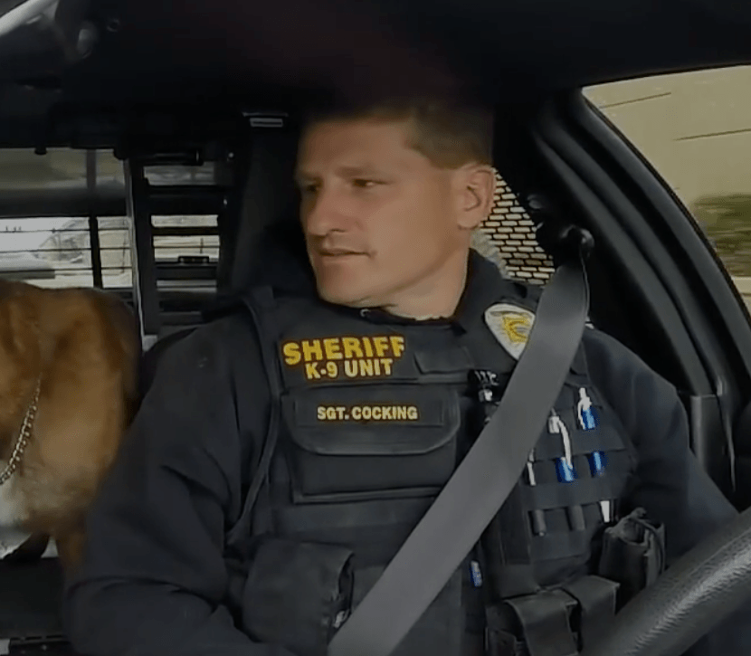 A man in a sheriff uniform is sitting in a car