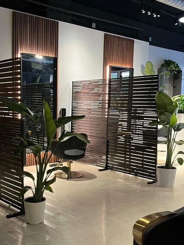 Modern indoor lounge with potted plants, woven screens, and warm wood accents in a minimalist showroom