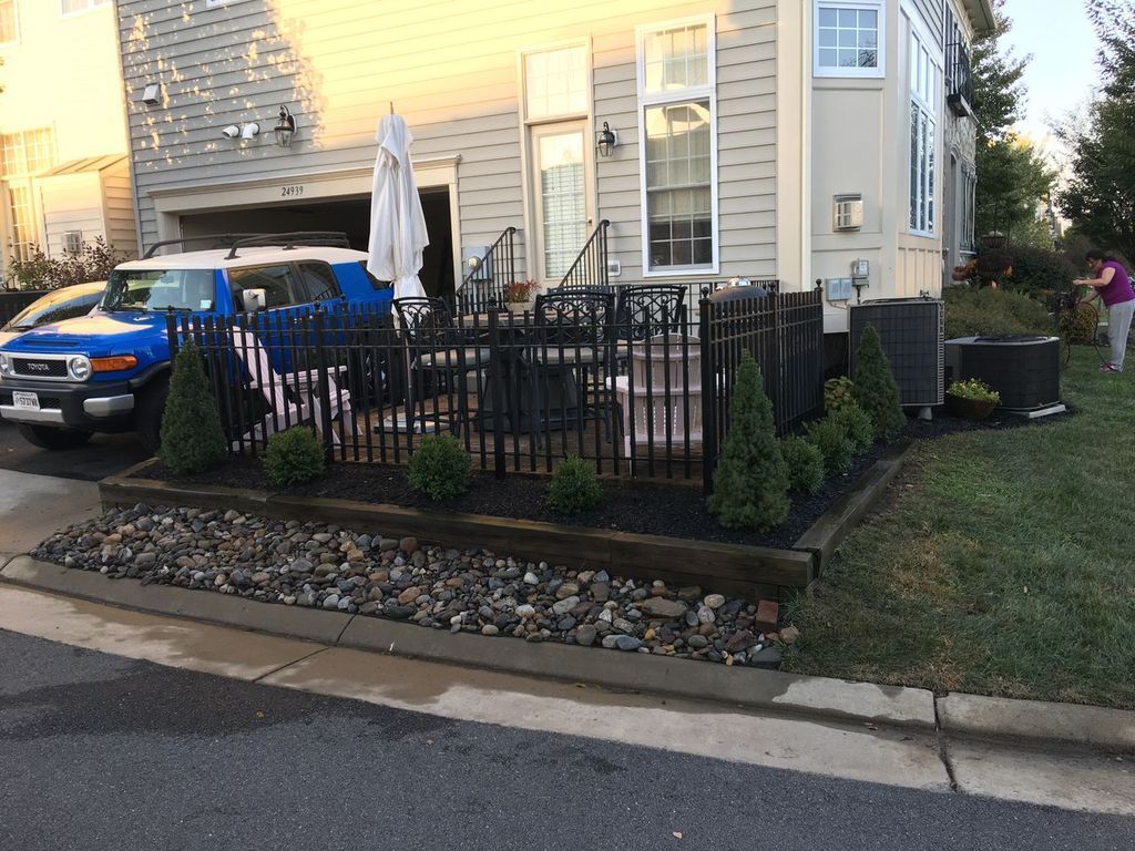 Blue SUV parked by a beige house with a black fence, patio, and umbrella at dusk