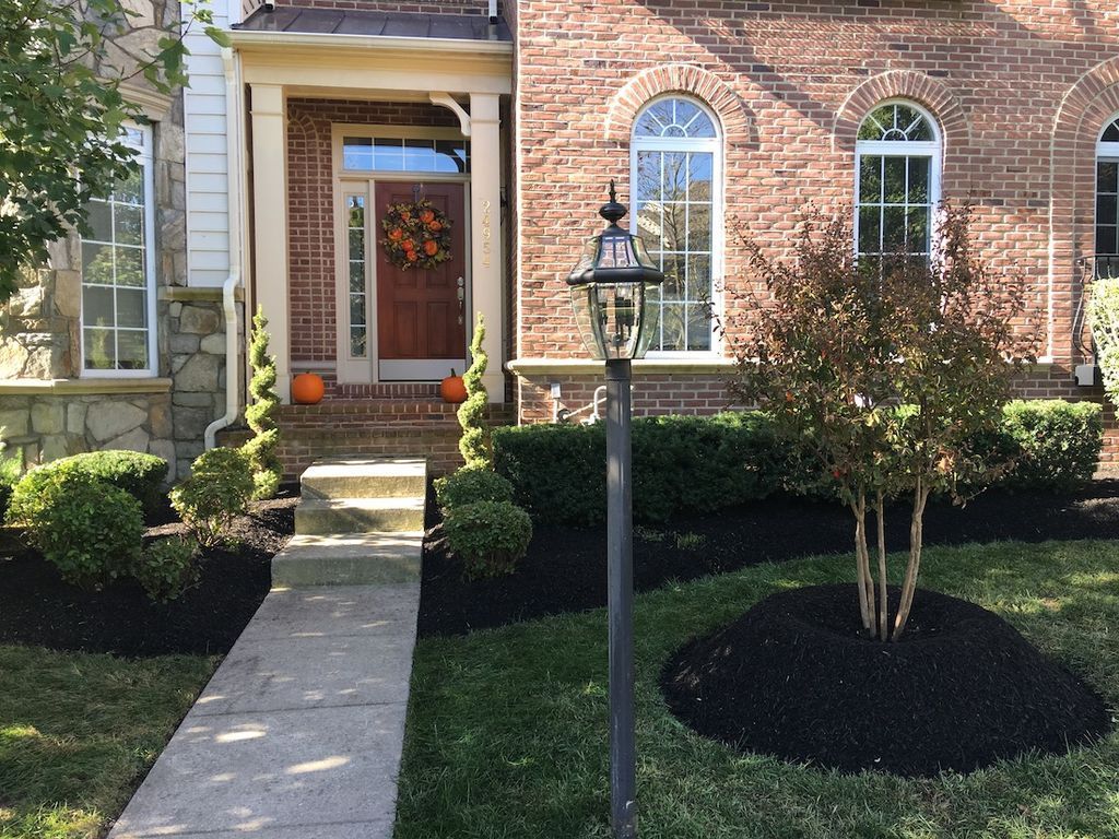 Brick house front entrance with stone path, lantern, and autumn decor.