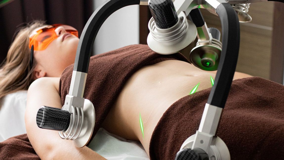 Person receiving laser hair removal treatment on the abdomen with orange goggles and a brown towel