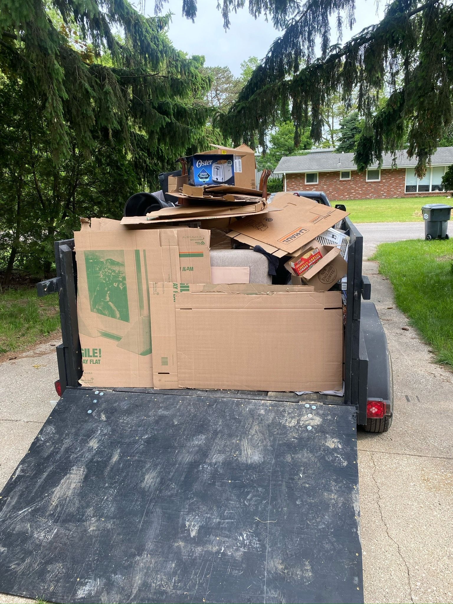 A trailer full of cardboard boxes is parked on the side of the road