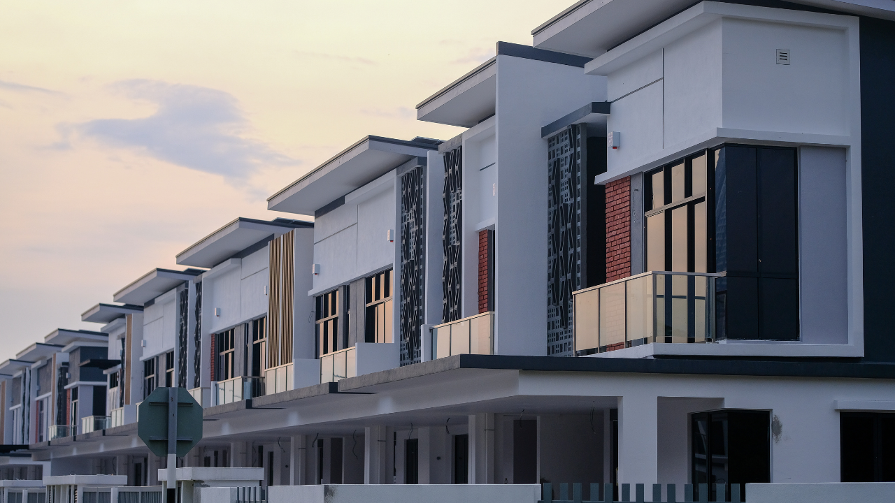 Row of modern white townhouses with dark windows at sunset