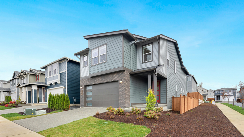 Modern gray two-story house with garage on a suburban street under a blue sky