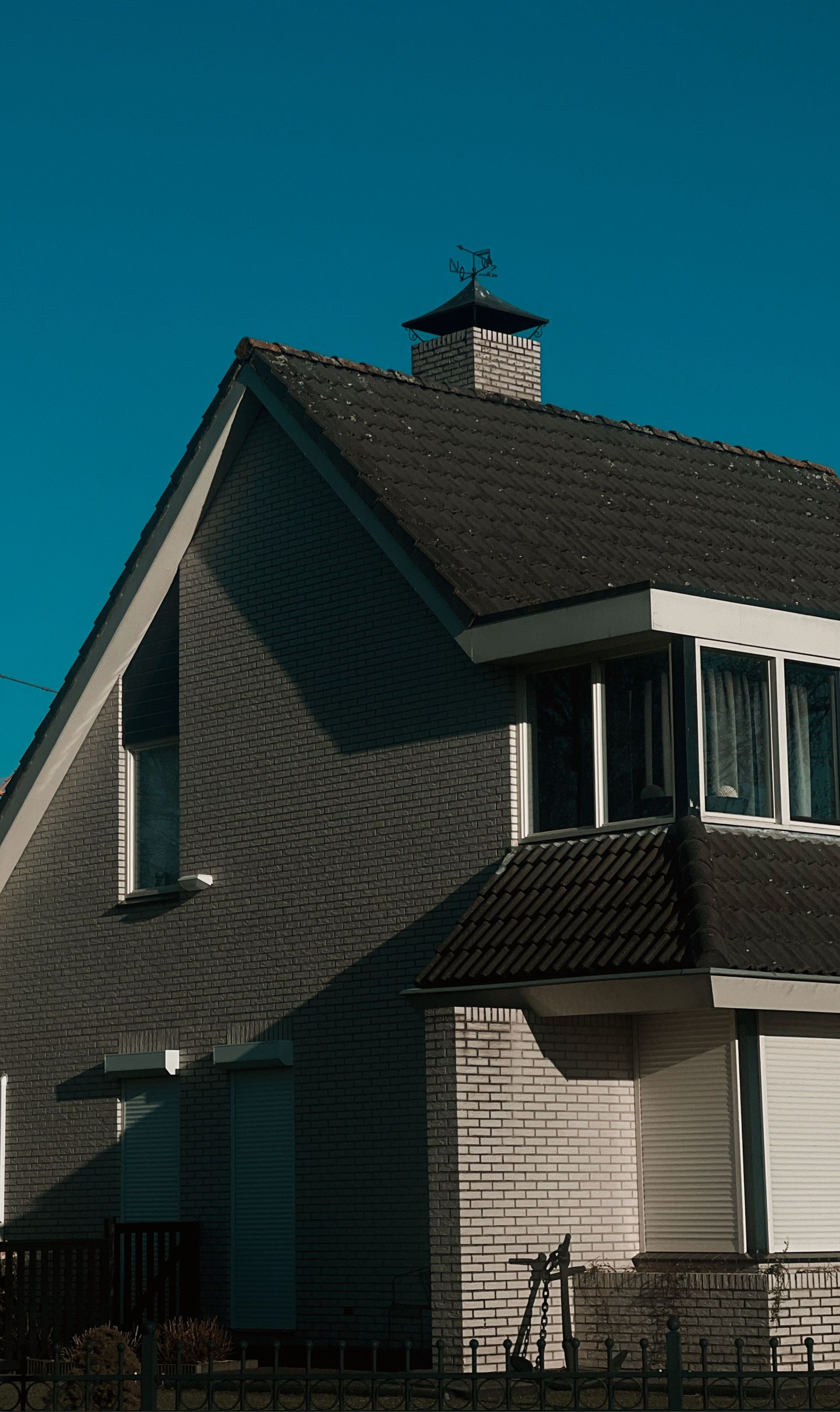 House with dark shingled roof against a blue sky