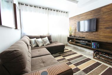 Living room with brown sectional sofa, TV, and wood accent wall.