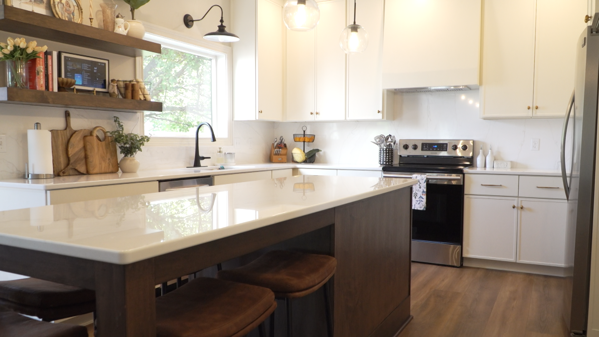 Bright modern kitchen with white cabinets, island, stainless stove, and wood flooring