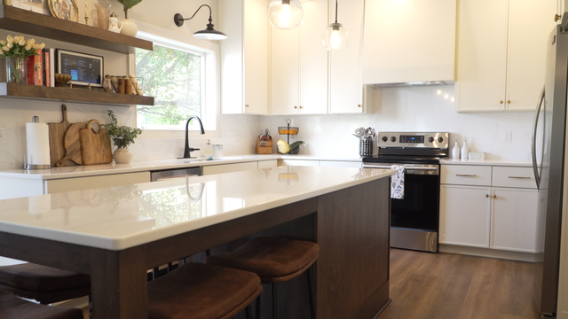 Bright modern kitchen with white cabinets, island, stainless stove, and wood flooring