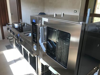 Cucina moderna in acciaio inox con ampio forno, piano cottura e bancone in una stanza luminosa