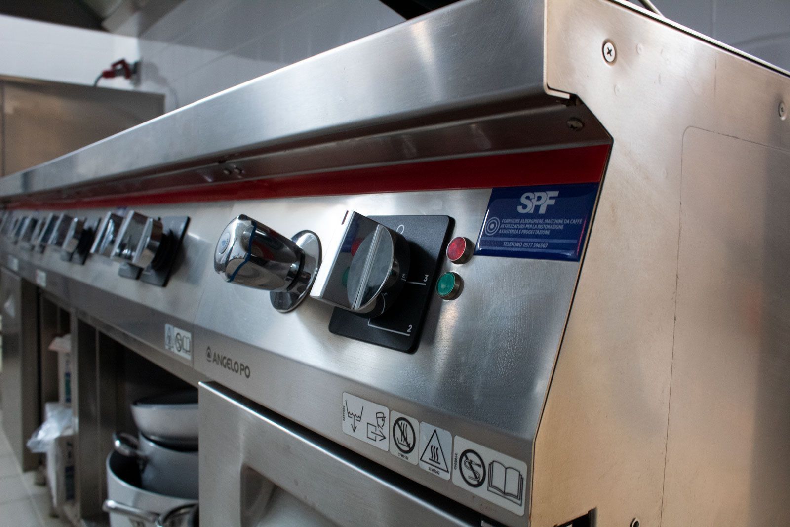 Pannello di controllo per griglia professionale in acciaio inox con manopole e quadranti, installato in una cucina.
