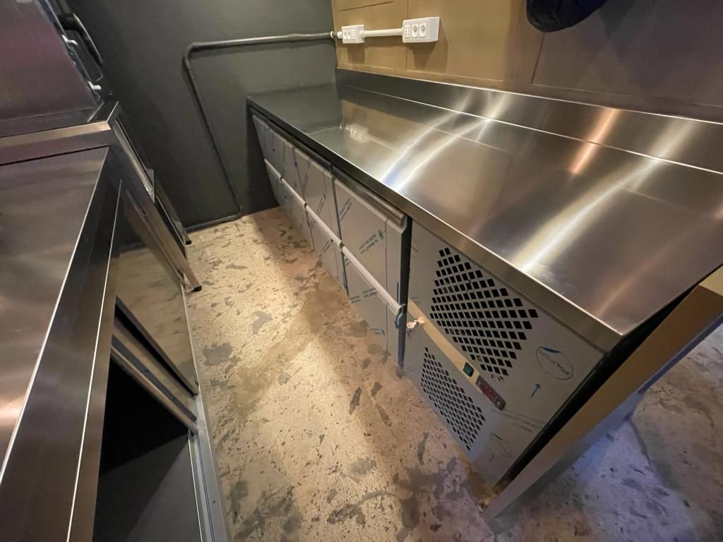 Bancone in acciaio inox con pannello ventilato e porta stretta con telaio metallico in una zona cucina