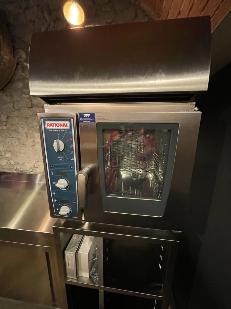 Forno da banco professionale in acciaio inox con sportello in vetro e pannello di controllo blu, installato in una cucina.