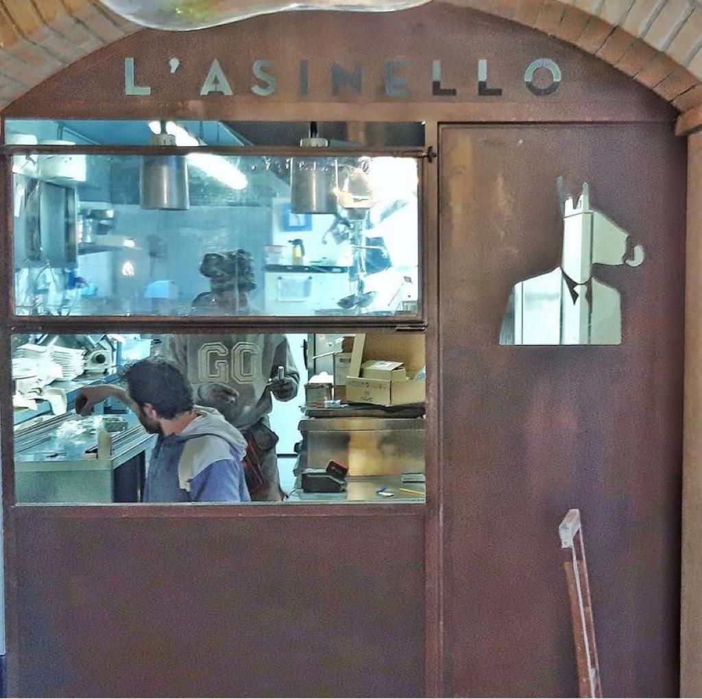 Bancone del caffè L'ASINELLO con una persona che lavora all'interno e un manichino in esposizione sulla destra.