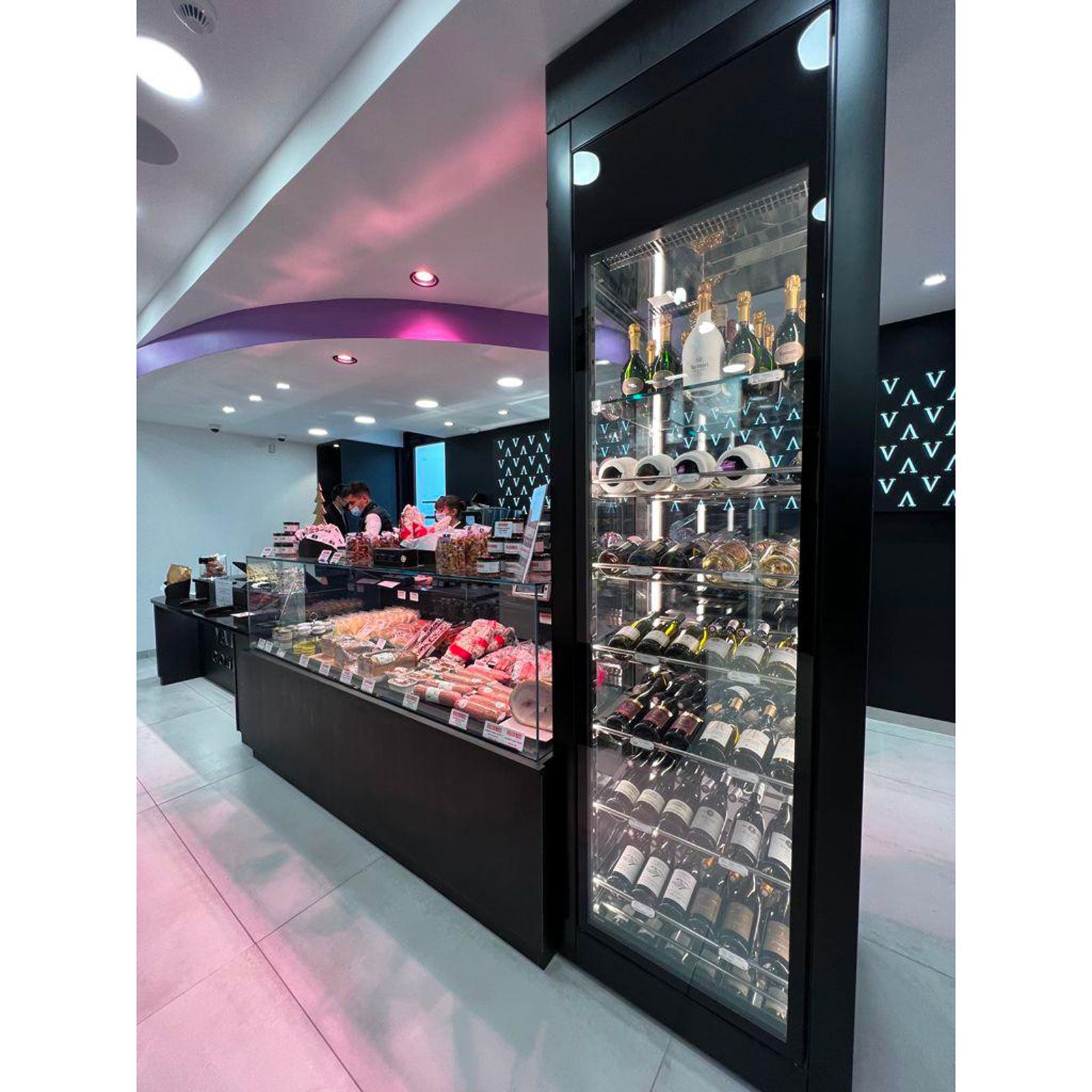 Interno moderno di una panetteria o pasticceria con vetrine di dolci e pasticcini illuminate da luci rosa e bianche.