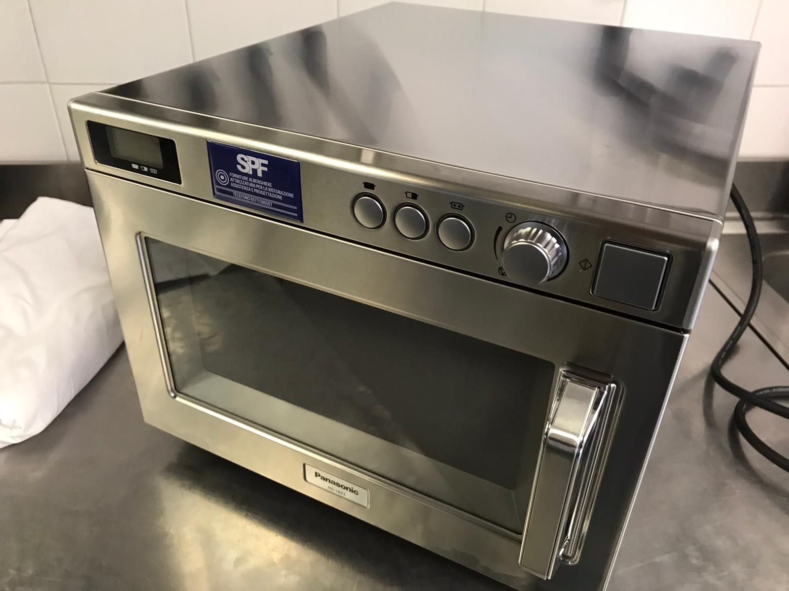 Forno a microonde da appoggio in acciaio inox con display digitale e manopole di controllo su superficie bianca.