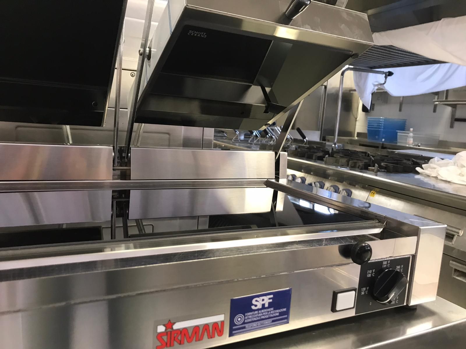 Griglia da cucina professionale in acciaio inox con coperchi apribili e manopole di controllo, vista frontalmente.