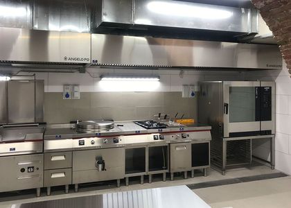Cucina professionale in acciaio inox completa di fornelli, lavelli e cappa aspirante, vuota e pulita.