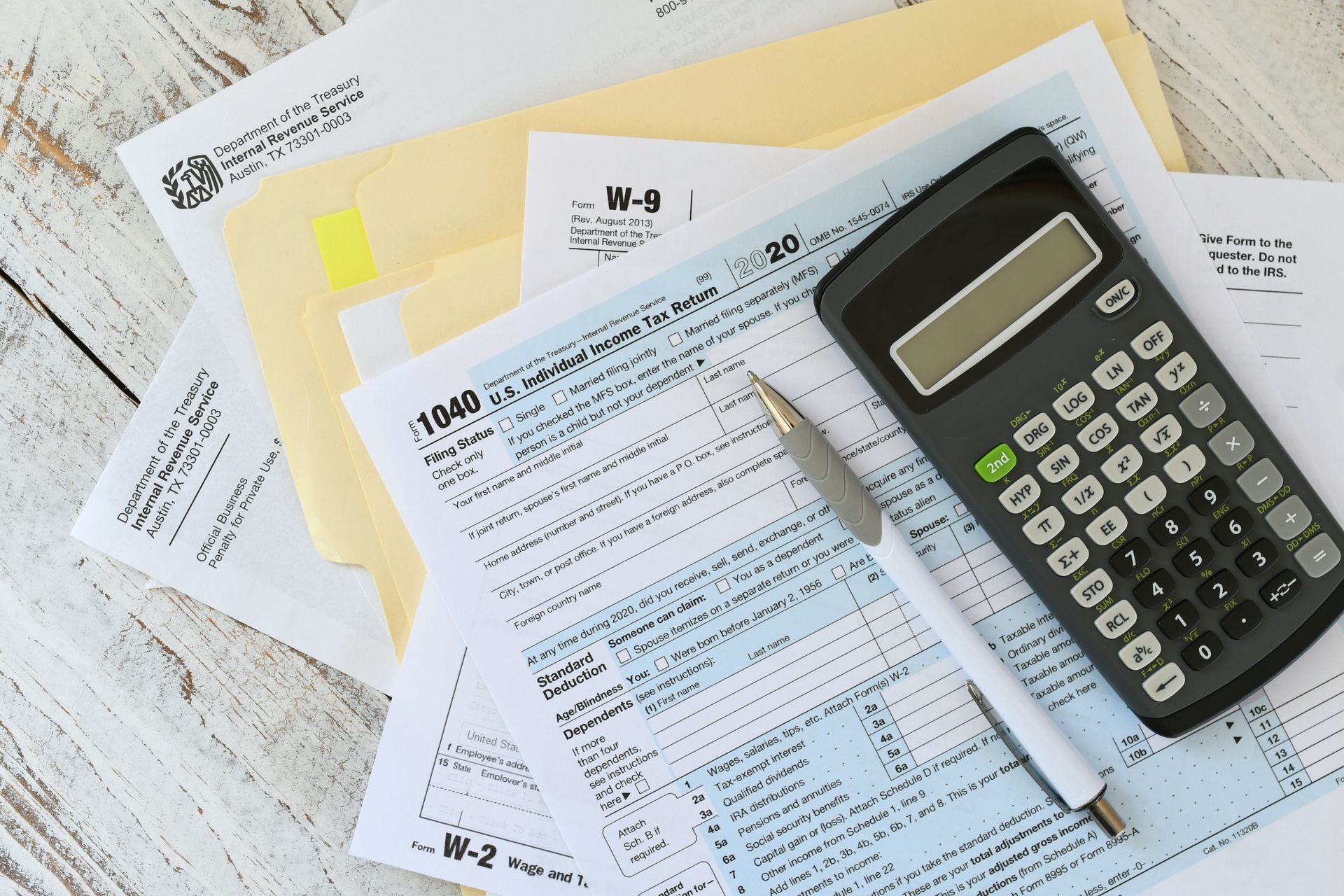 Tax forms, calculator, and pen on a table, ready for tax preparation.