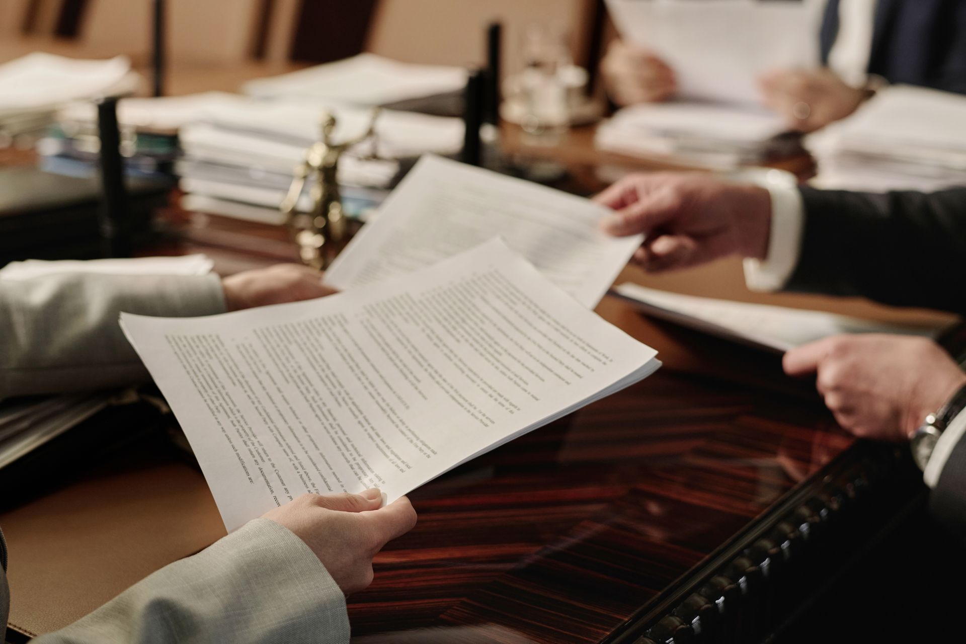 People holding and exchanging documents at a table.