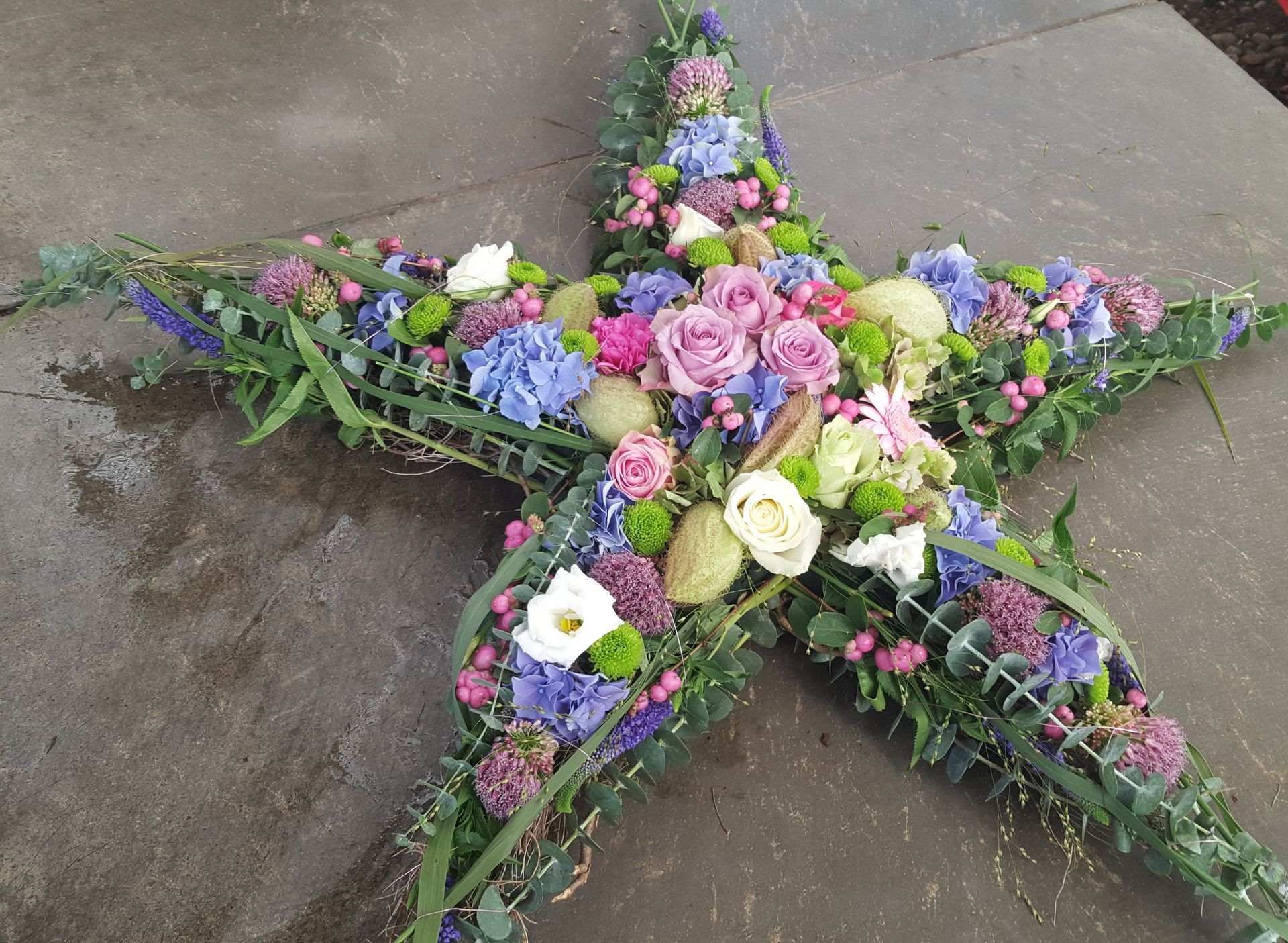 Auf einer Betonoberfläche steht ein sternförmiges Blumenarrangement.
