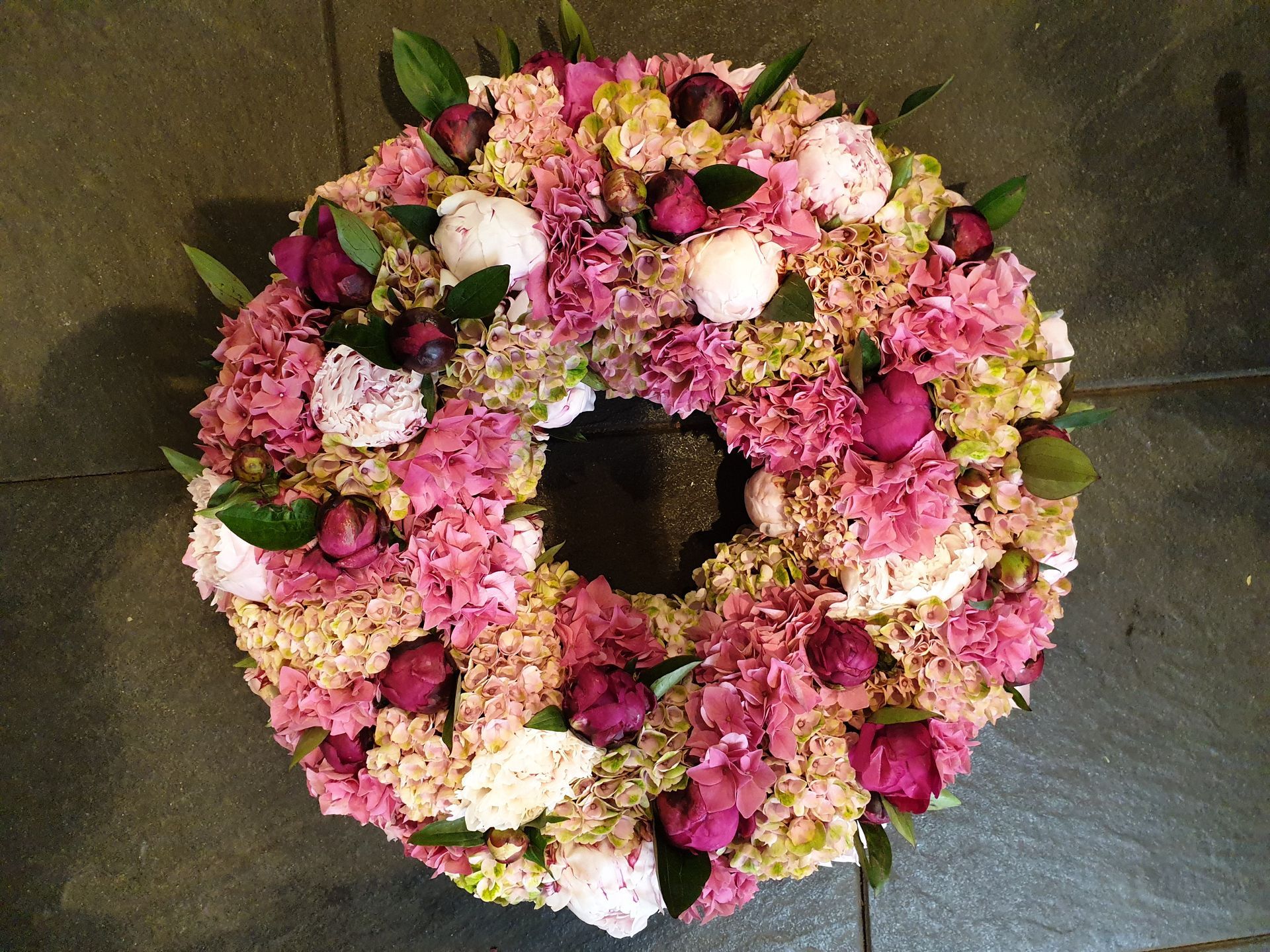 Ein Kranz aus rosa und weißen Blumen auf einem gefliesten Boden