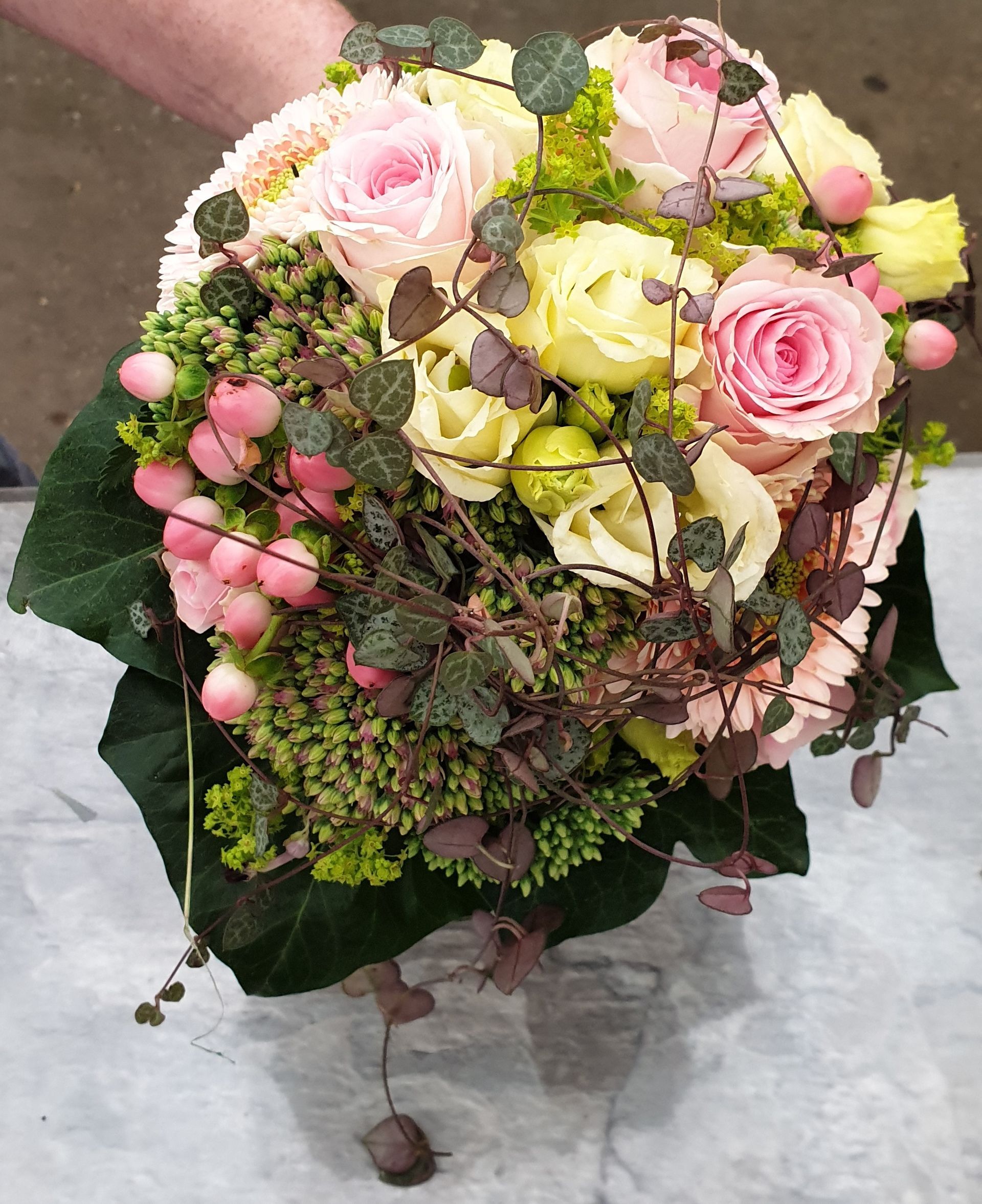 Ein Strauß rosa und gelber Blumen steht auf einem Tisch