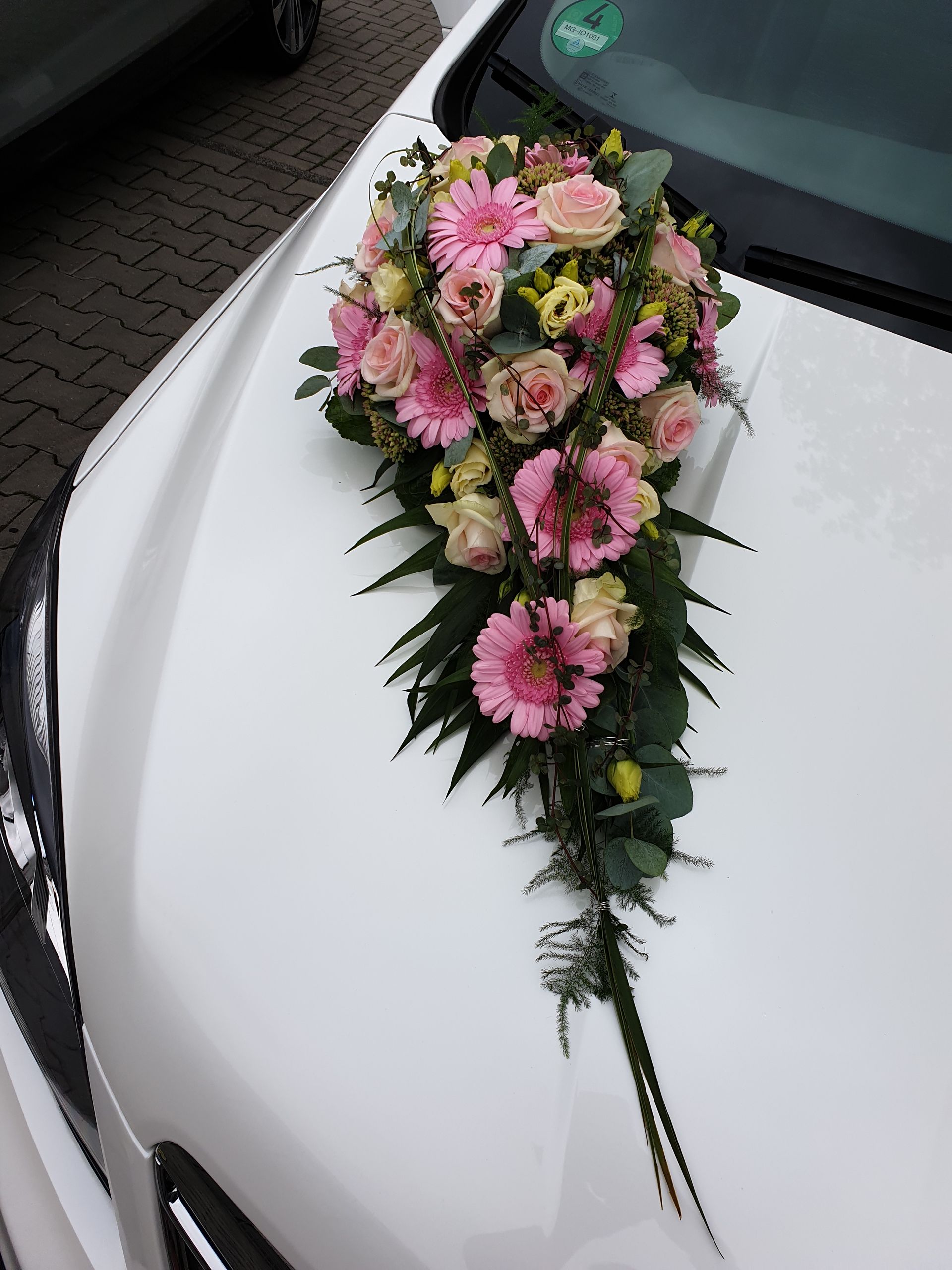 Ein weißes Auto mit rosa und gelben Blumen auf der Motorhaube