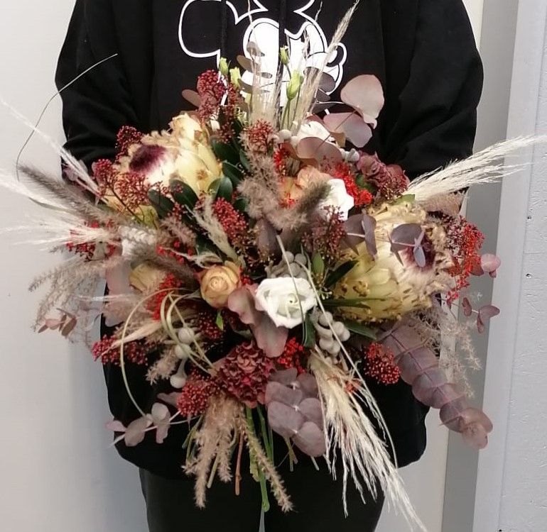 Eine Person in einem schwarzen Sweatshirt hält einen Blumenstrauß