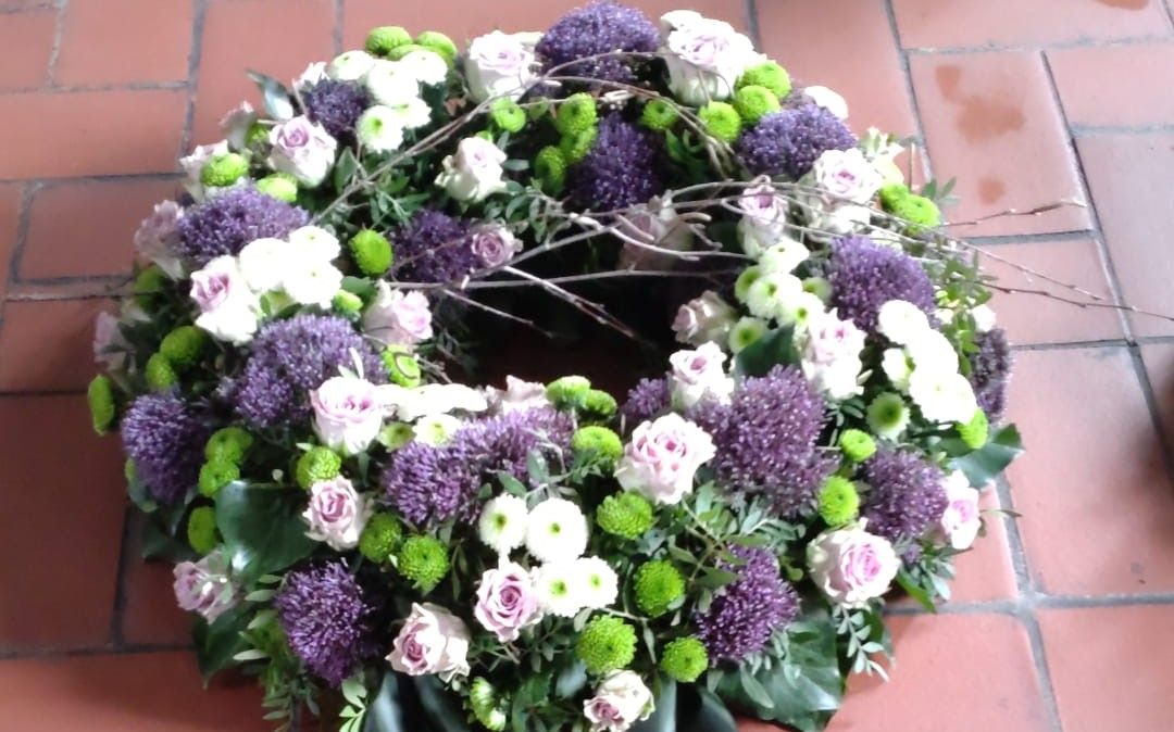Ein Kranz aus lila und weißen Blumen auf einem gefliesten Boden