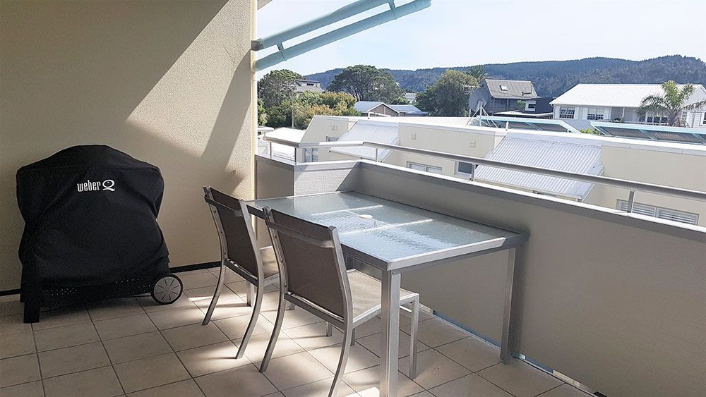 A balcony with a table and chairs and a grill.