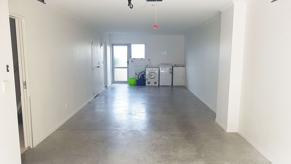 A large empty garage with a washer and dryer in it.