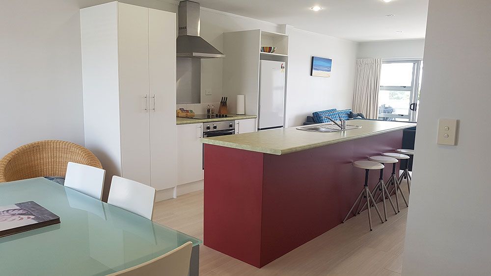 A kitchen with a red island and a dining table and chairs.