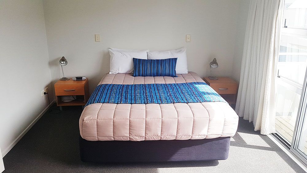 There is a bed in the middle of the room with a window.