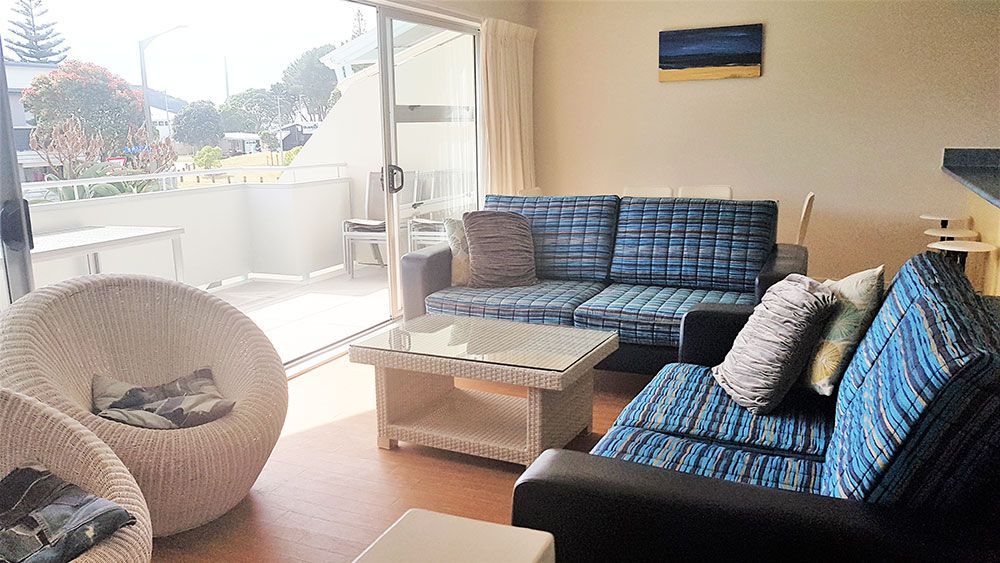 A living room with a couch , chairs , and a table.