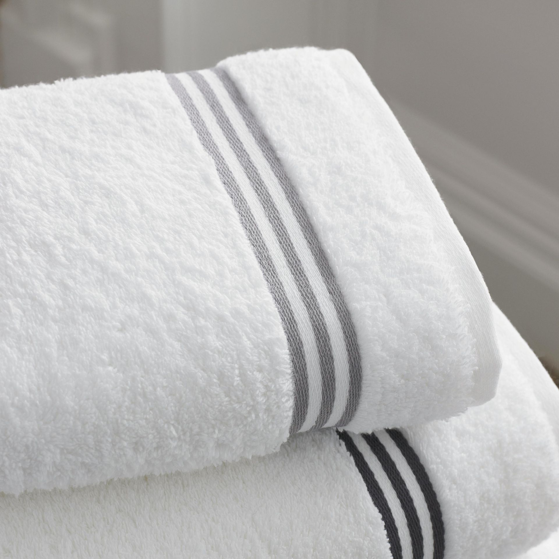 A stack of white towels with grey stripes on them