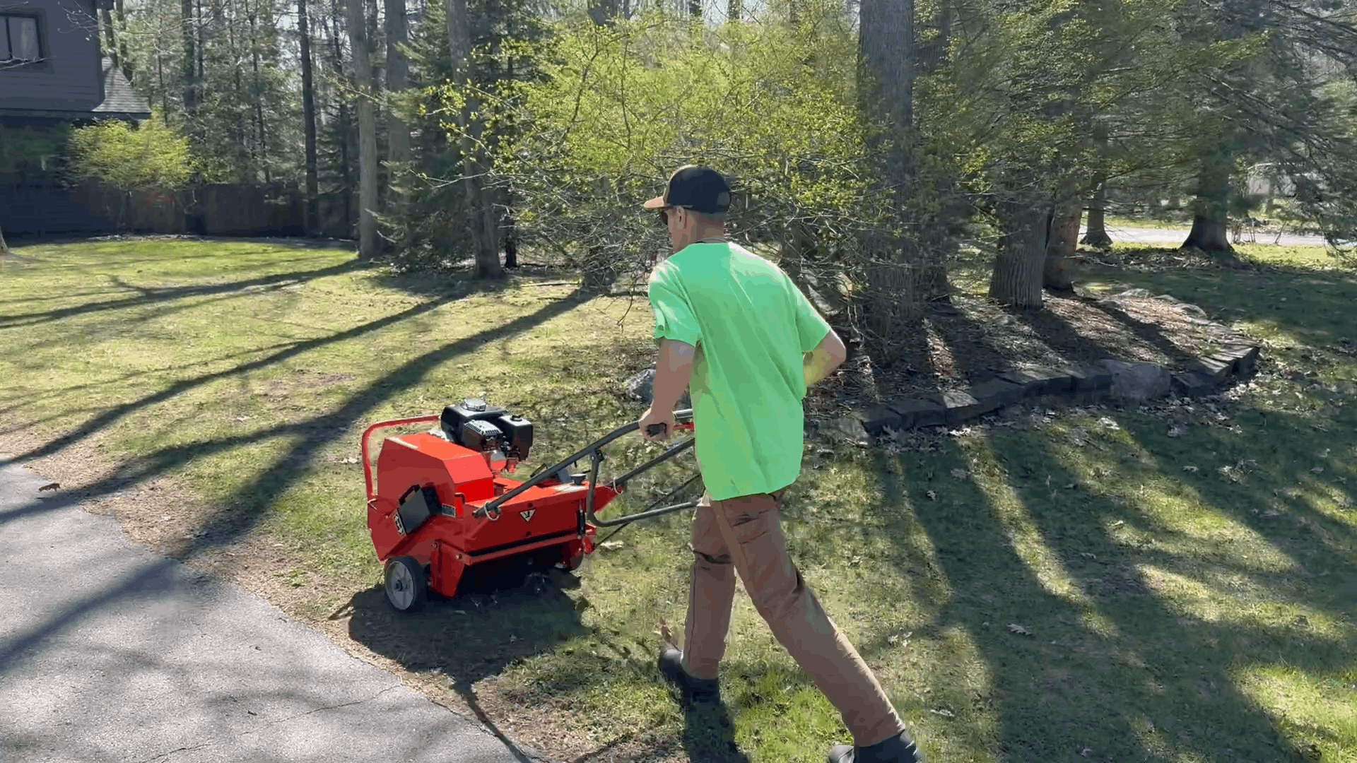 A red lawn aerator is working on a lush green lawn.