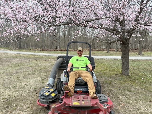 A man is riding a lawn mower on a lush green lawn.