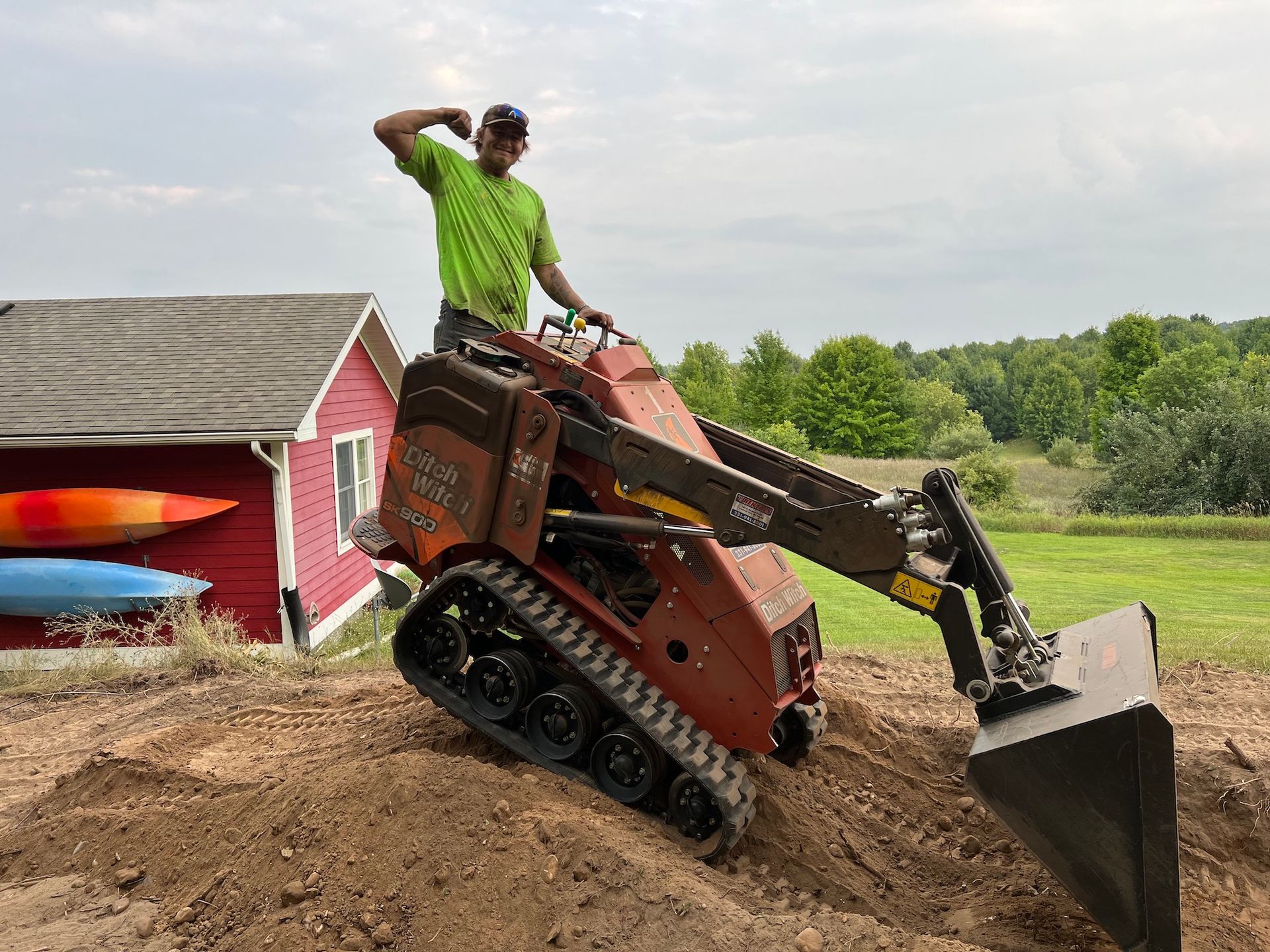 A man in a green shirt is standing next to a small bulldozer.