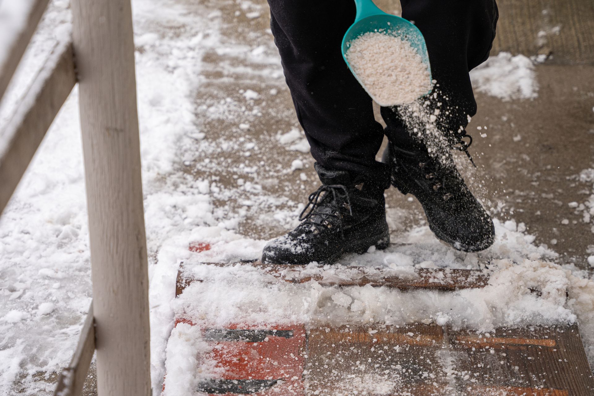A person is shoveling snow off of a set of stairs.