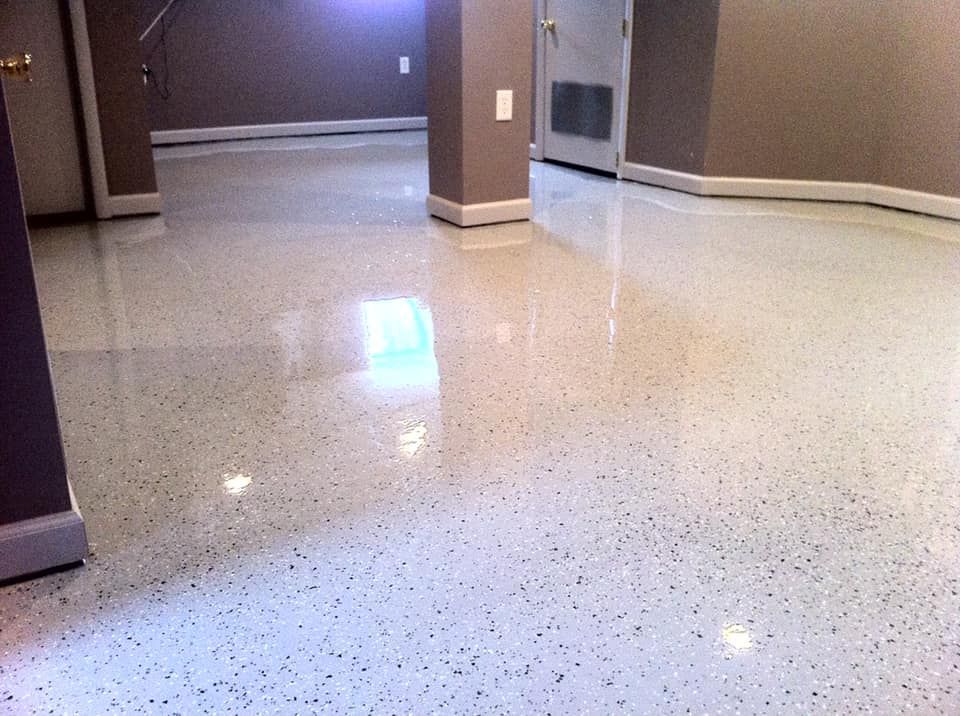 A room with a polished, speckled white epoxy floor, light-colored walls, and a central support pillar.