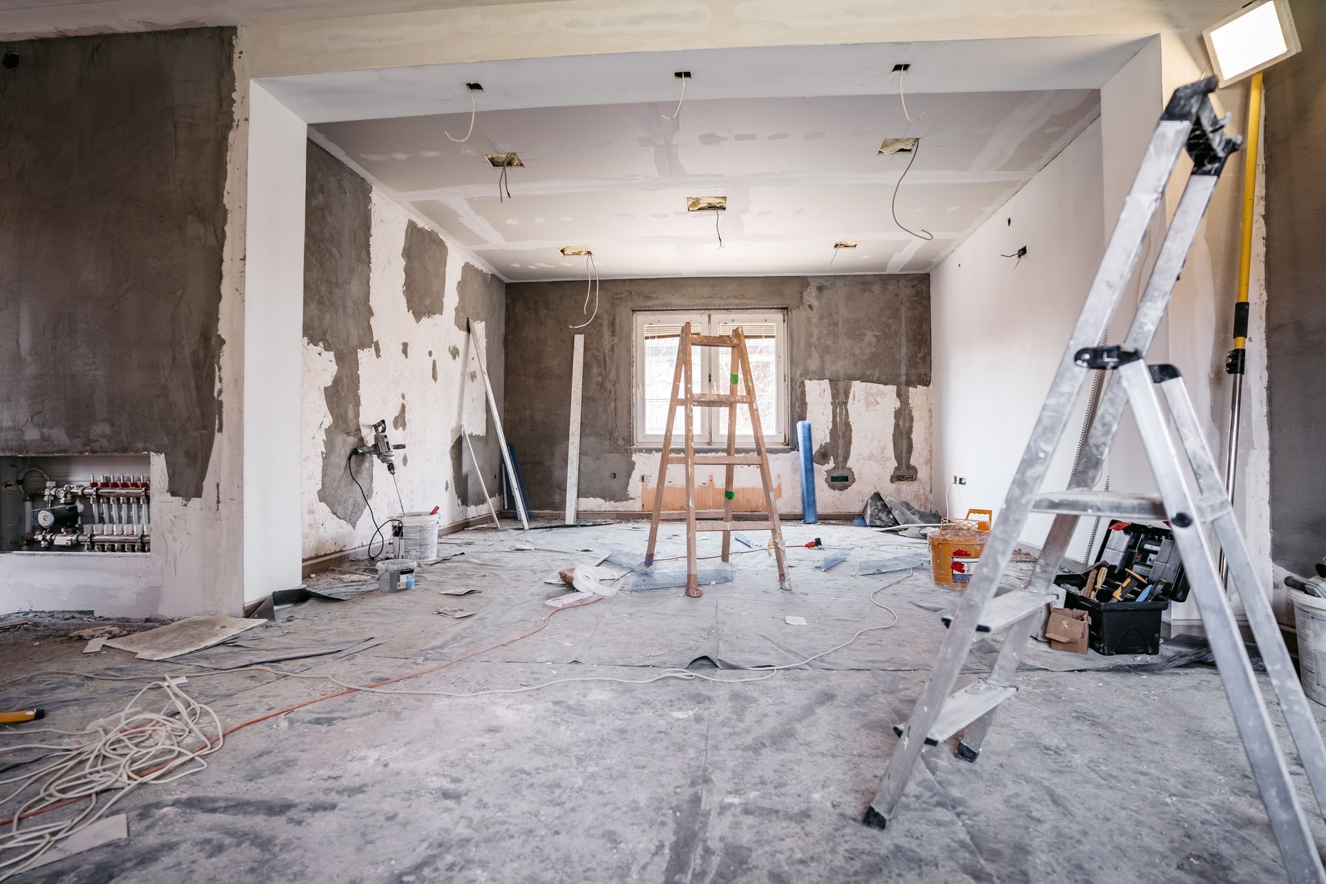 Interior room under construction with ladders, tools, and exposed walls.