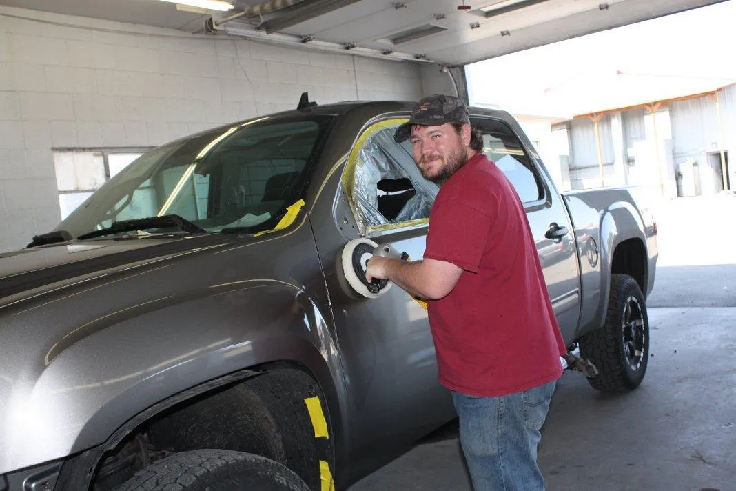 A man in a red shirt is polishing a truck