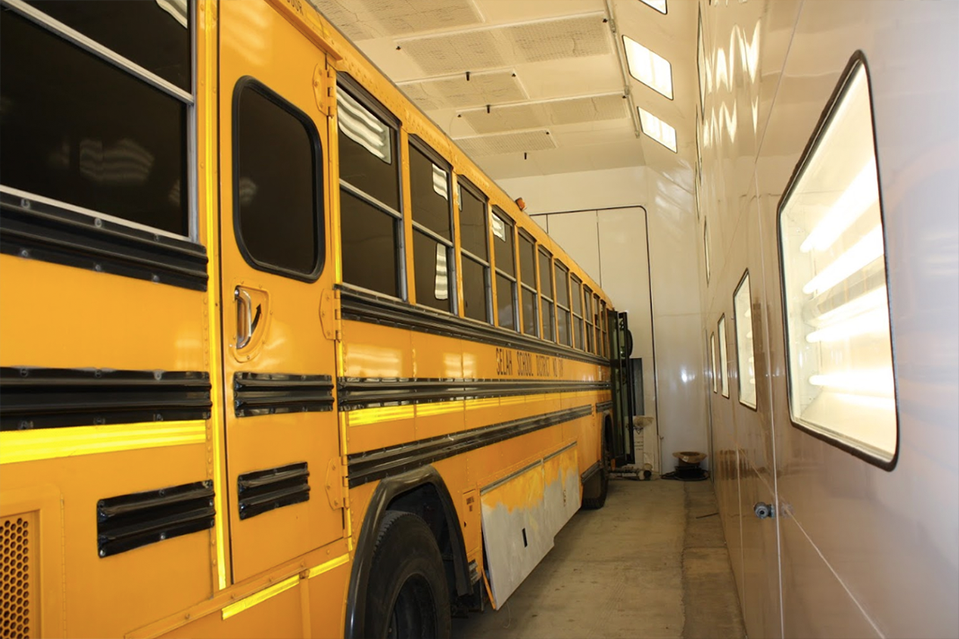 A yellow school bus is parked in a garage
