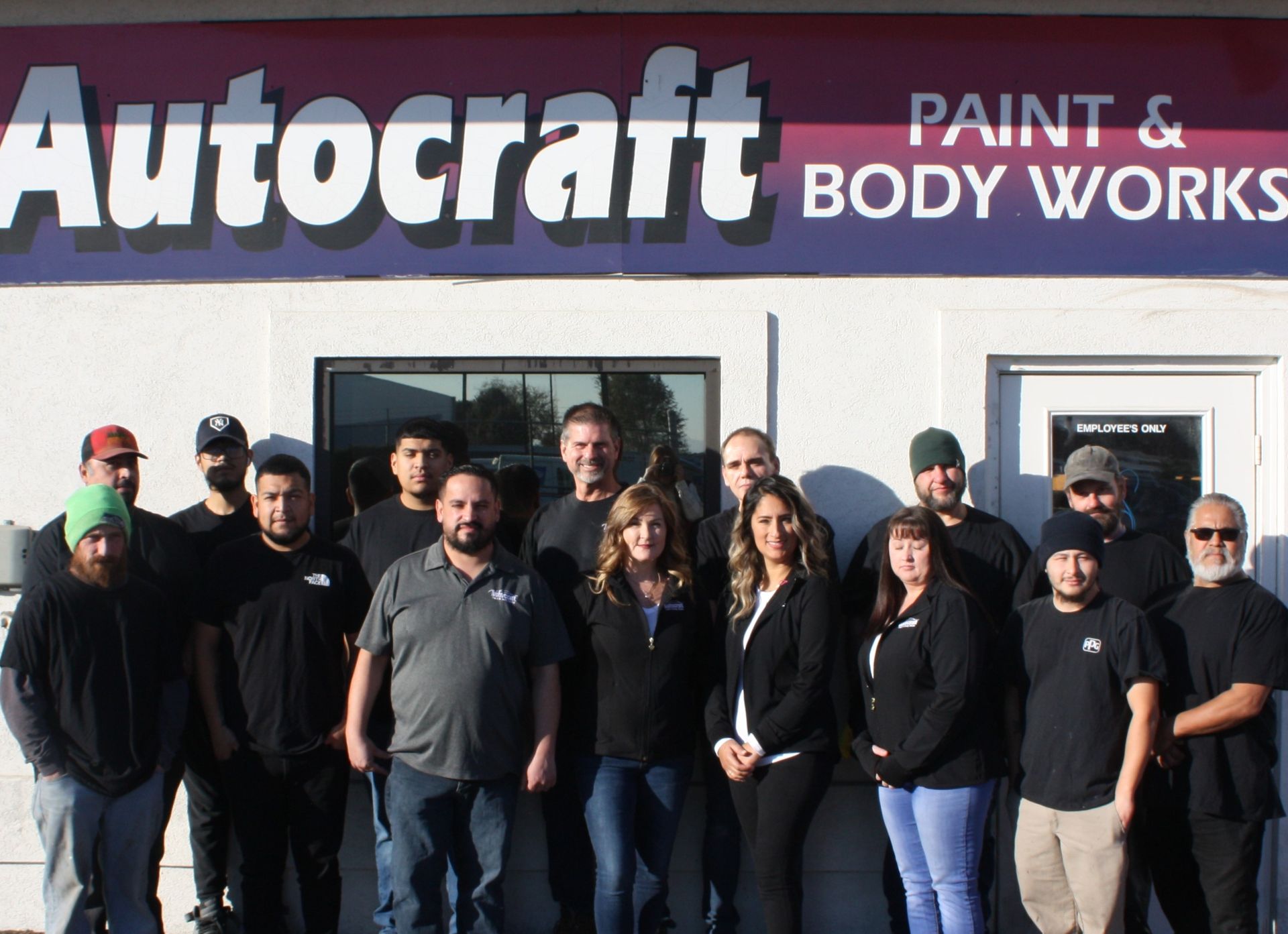 A group of people standing in front of a sign for autocraft paint and body works